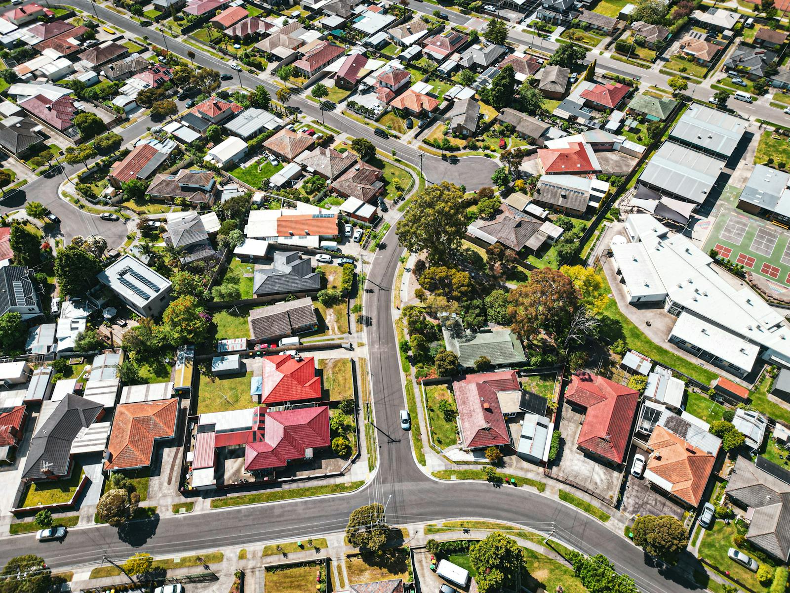 Drone shot capturing vibrant suburban area in Melbourne, Australia, showcasing varied architecture and greenery.