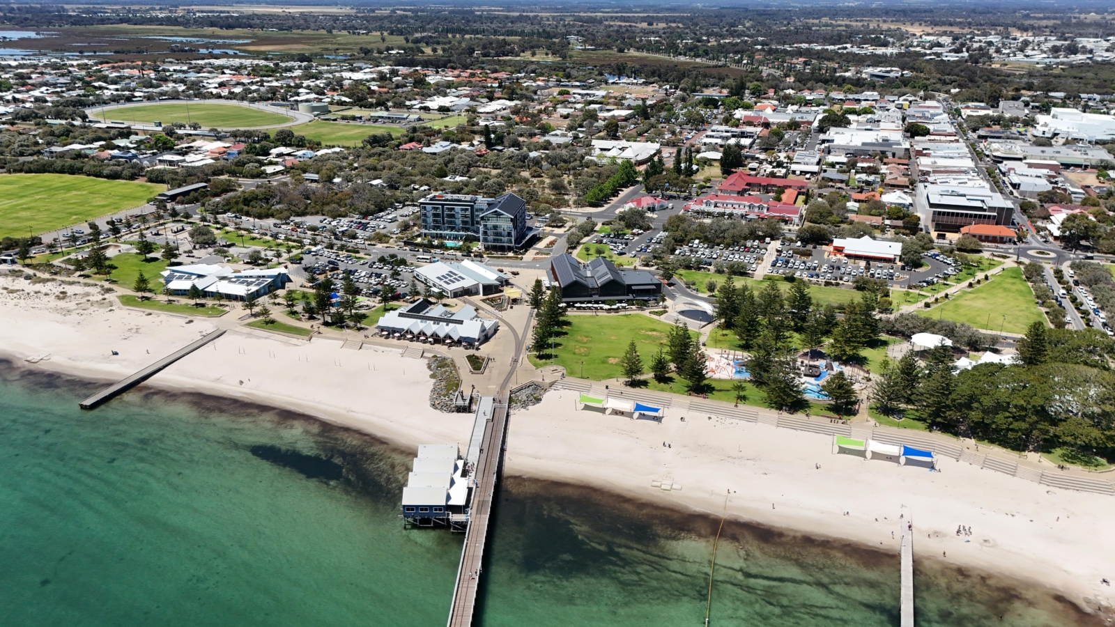 A stunning aerial view of Busselton's coastline in Western Australia, featuring clear skies and vibrant cityscapes.